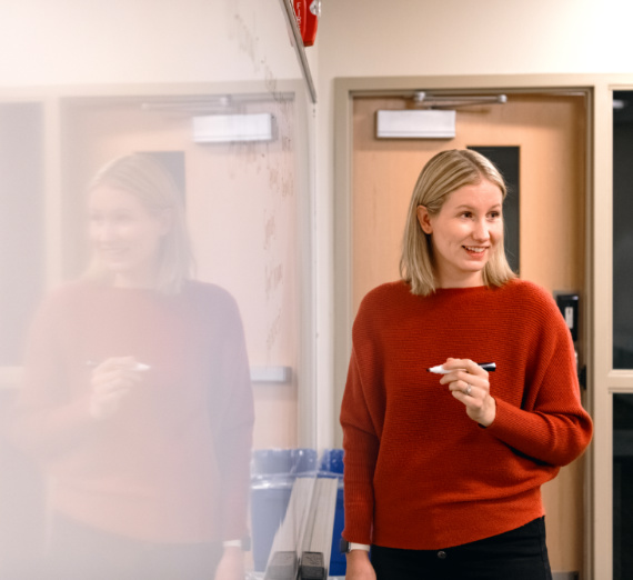 A woman with blond hair hands a Christmas stocking to a woman with long brown hair